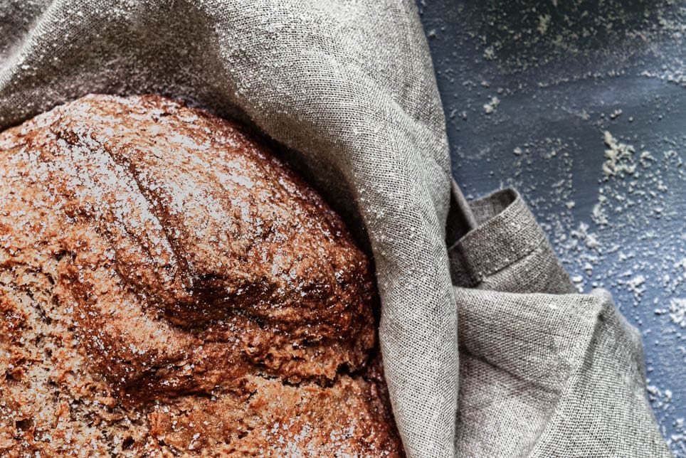 Ein Laib Sodabrot, daneben Mehl und ein Sieb