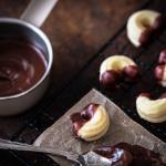 Mini Linzer Kipferl, die mit flüssiger Schokolade aus einer kleinen Kaserolle überzogen werden