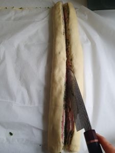 Zusammengerollter Pizzateig wird durchgeschnitten