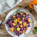 Rotkohlsalat mit Papaya auf einem Teller und Holztisch