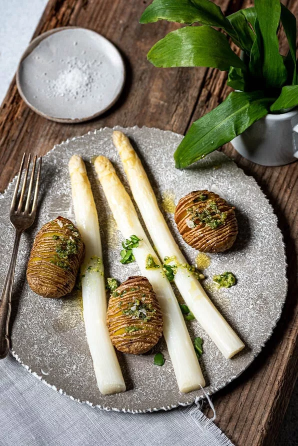 Fächerkartoffeln mit Bärlauchpesto und weißem Spargel auf einem Teller