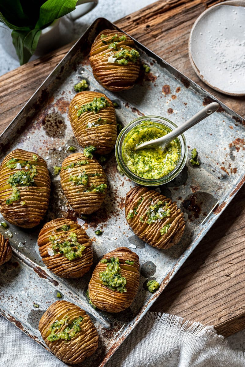 Hasselback Kartoffeln sind mit einem Glas Pesto auf einem Tablett