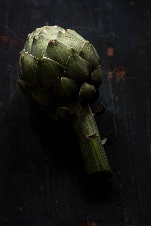 Eine Artischocke liegt auf Holzuntergrund