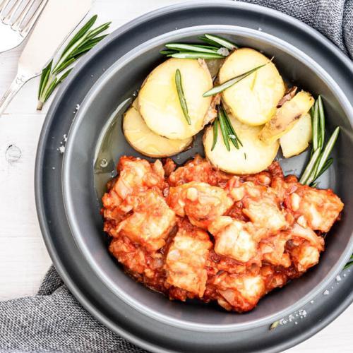 Ein Teller mit Baccala alla livornese und Rosmarinkartoffeln