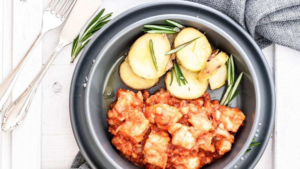 Ein Teller mit Baccala alla livornese und Rosmarinkartoffeln