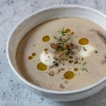 Cremige Maronensuppe in einer Suppenschale mit Edelkastanien daneben.