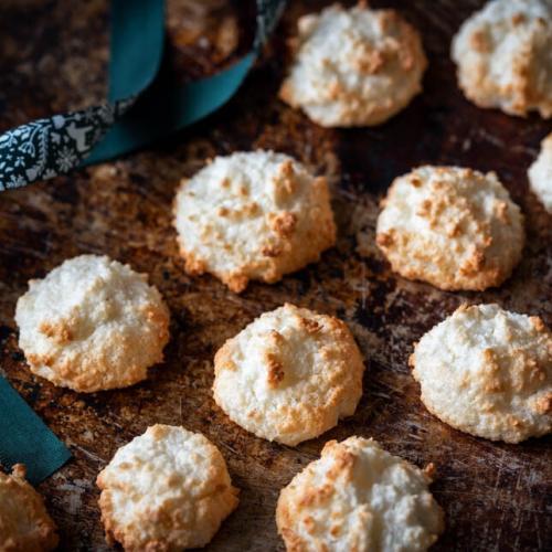 Kokosmakronen liegen auf einem alten Backblech neben einer Schleife