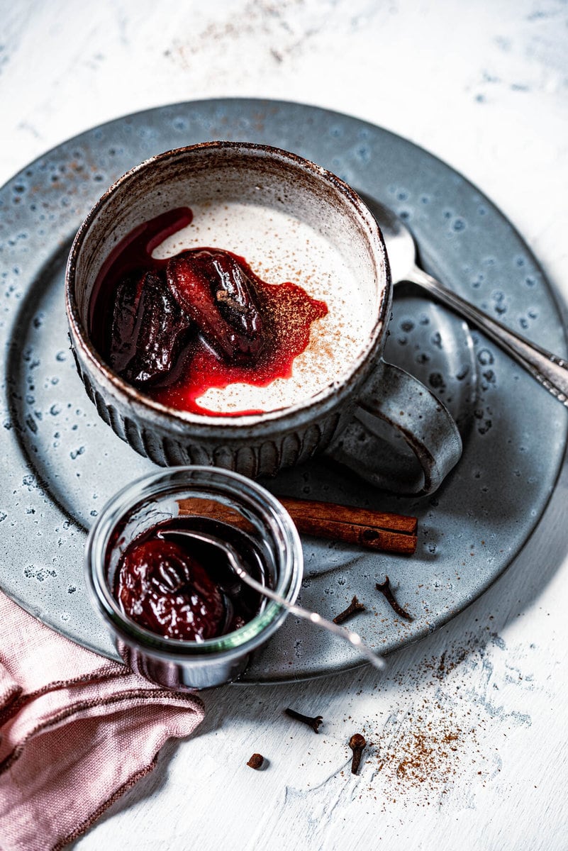 Lebkuchen Panda Cotta ist in einer Tasse mit karamellisierten Pflaumen angerichtet