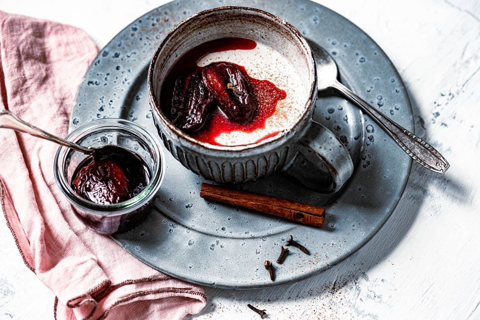 Lebkuchen Panda Cotta ist in einer Tasse mit karamellisierten Pflaumen angerichtet