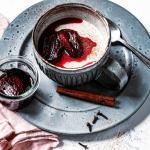 Lebkuchen Panda Cotta ist in einer Tasse mit karamellisierten Pflaumen angerichtet