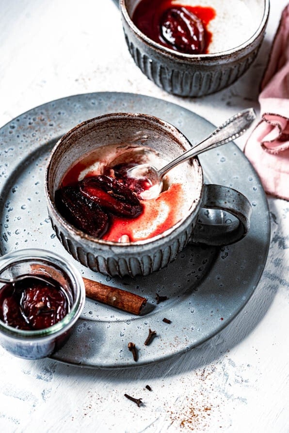 Lebkuchen Panda Cotta ist in einer Tasse mit karamellisierten Pflaumen angerichtet