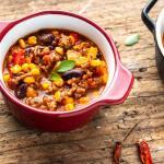 Zwei Schälchen mit Chili con carne auf einem Holzuntergrund