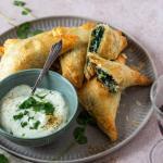 Gefüllte Blätterteigtaschen liegen auf einem Teller und 2 Weingläser stehen daneben