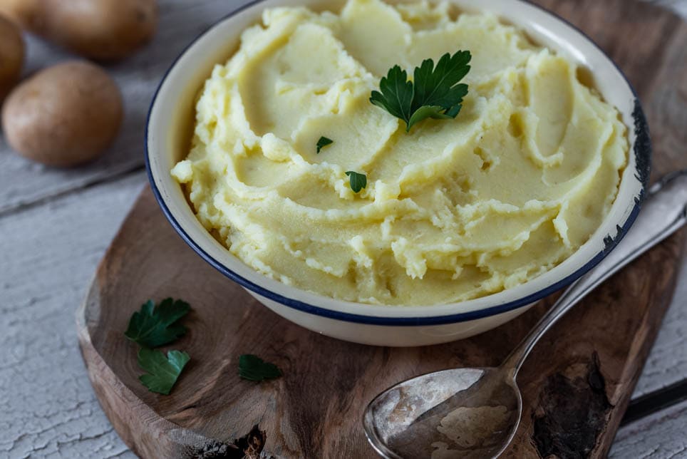 Kartoffelpüree in einer Schale auf einem Holzbrett.