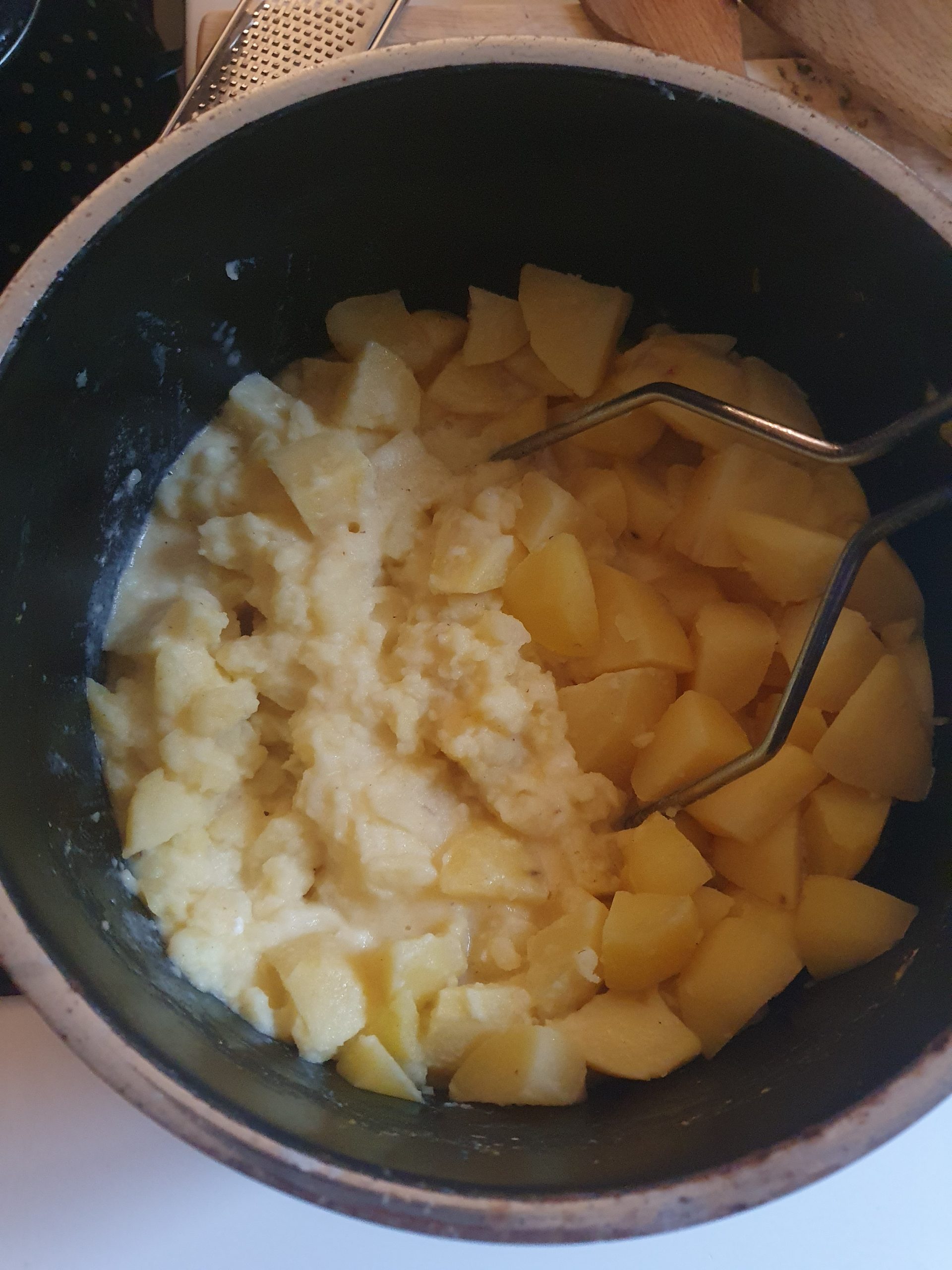 Kartoffelstückchen im Kochtopf mit Kartoffelstampfer