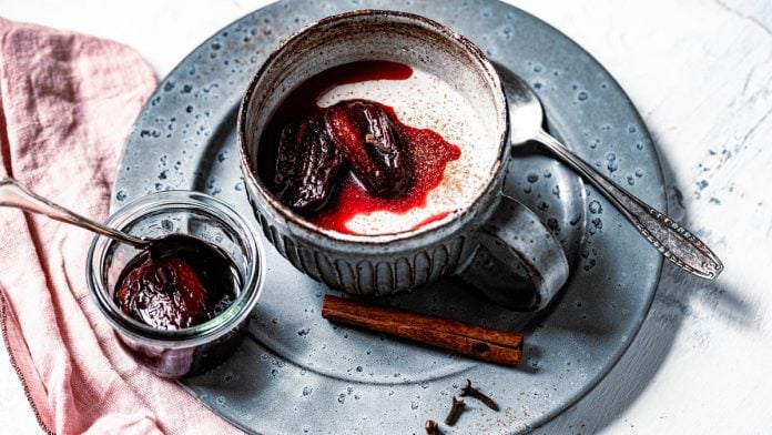 Lebkuchen Panda Cotta ist in einer Tasse mit karamellisierten Pflaumen angerichtet