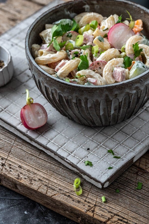 Eine Bowl mit Nudelsalat steht auf einem Bettchen mit Schälchen im Hintergrund