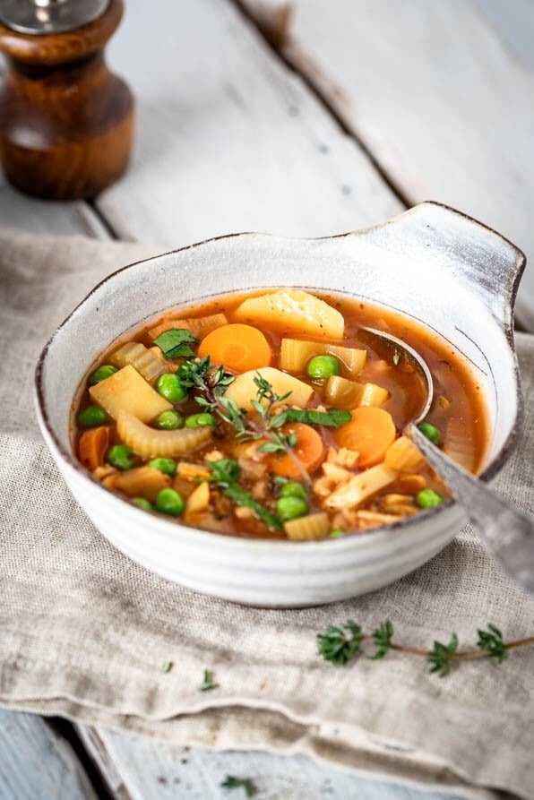 Eine Schüssel Eintopf auf einem Tisch mit einer Pfeffermühle.