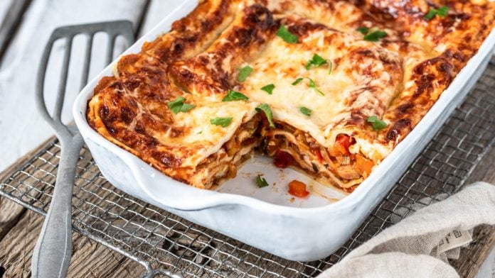 Angeschnittenes Ofengericht in Auflaufform auf Holzbrett