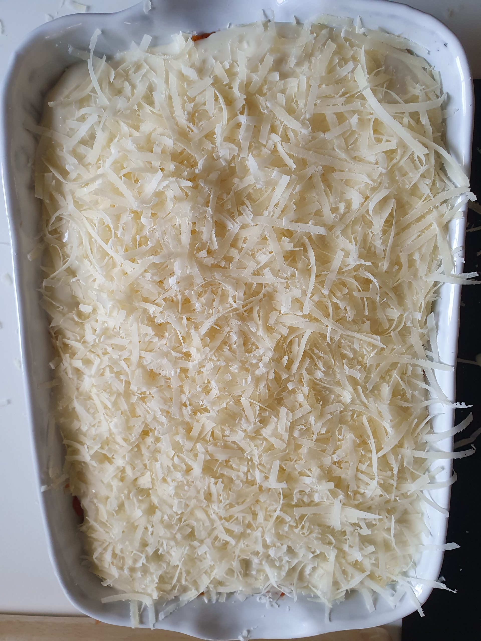 Auflaufform mit Lasagne und Parmesan obenauf.