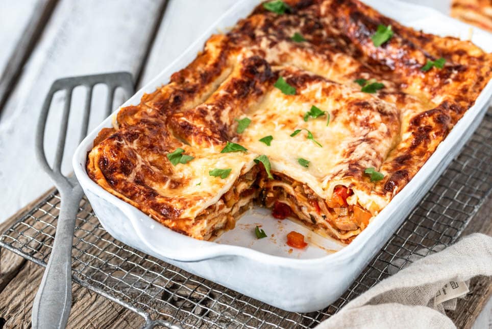 Angeschnittenes Ofengericht in Auflaufform auf Holzbrett