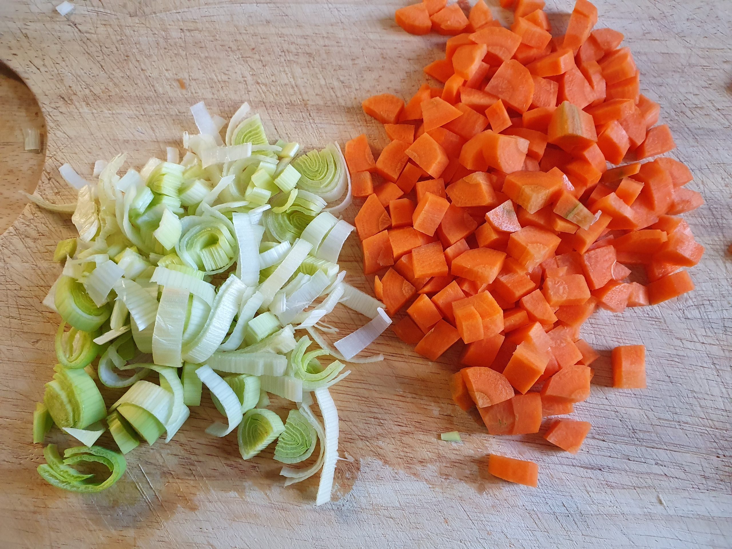 Gewürfelte Karotten und Lauch auf Schneidebrett