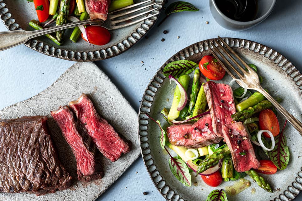 Zwei Teller mit Spargelsalat und ein Brettchen mit Rumpsteak.