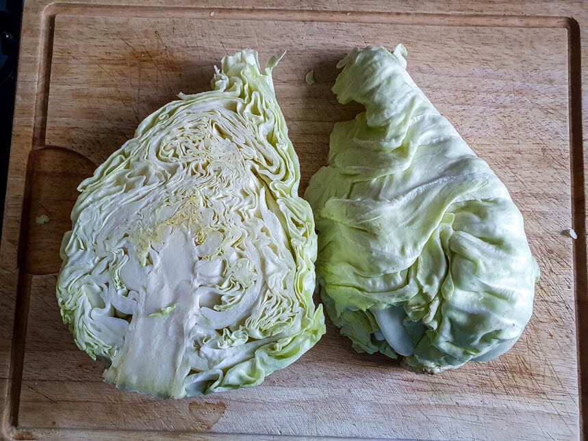 Ein halbierter Spitzkohl liegt auf einem Schneidebrett.