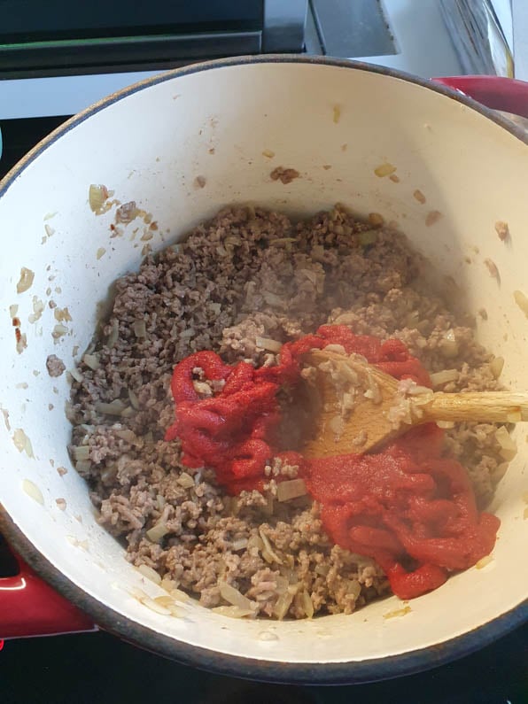 Tomatenmark wird zum Hackfleisch in Topf gegeben.