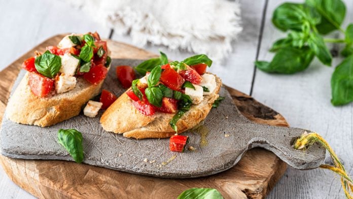 2 Stück Bruschetta mit Tomaten auf einem Brettchen