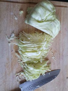 in Streifen geschnittener Spitzkohl auf Holzbrett