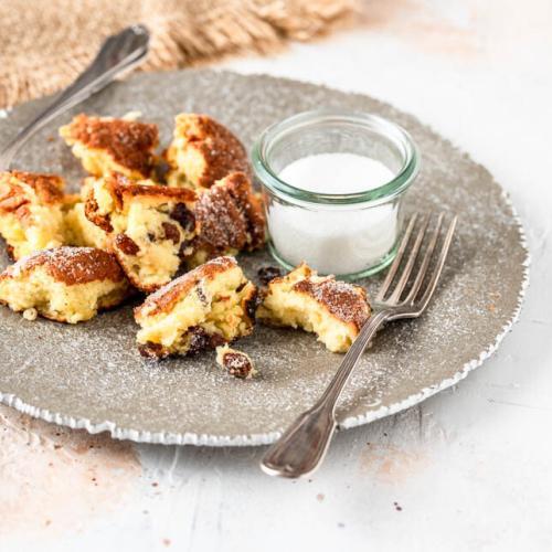 Ein Teller mit Kaiserschmarrn und Zucker auf hellem Untergrund