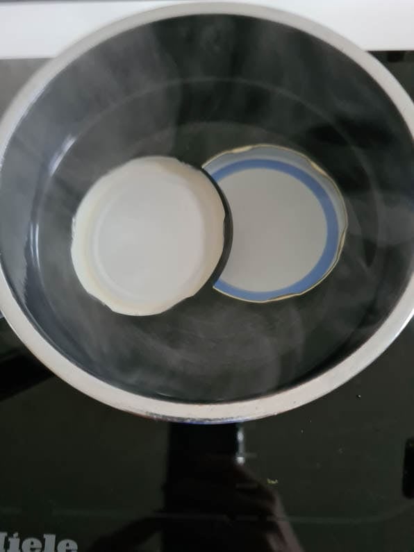 2 Deckel von Schraubgläsern liegen in einem Kochtopf