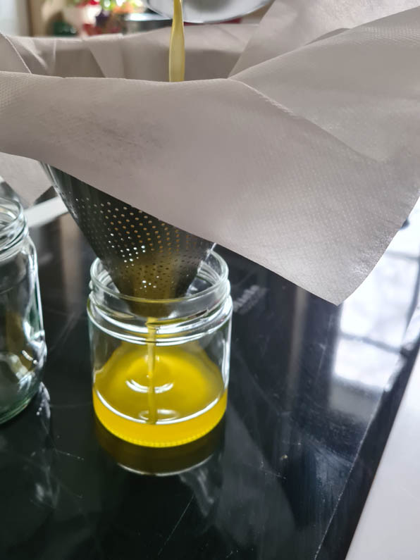 Butter wird durch Passiertuch in ein Glas gefüllt