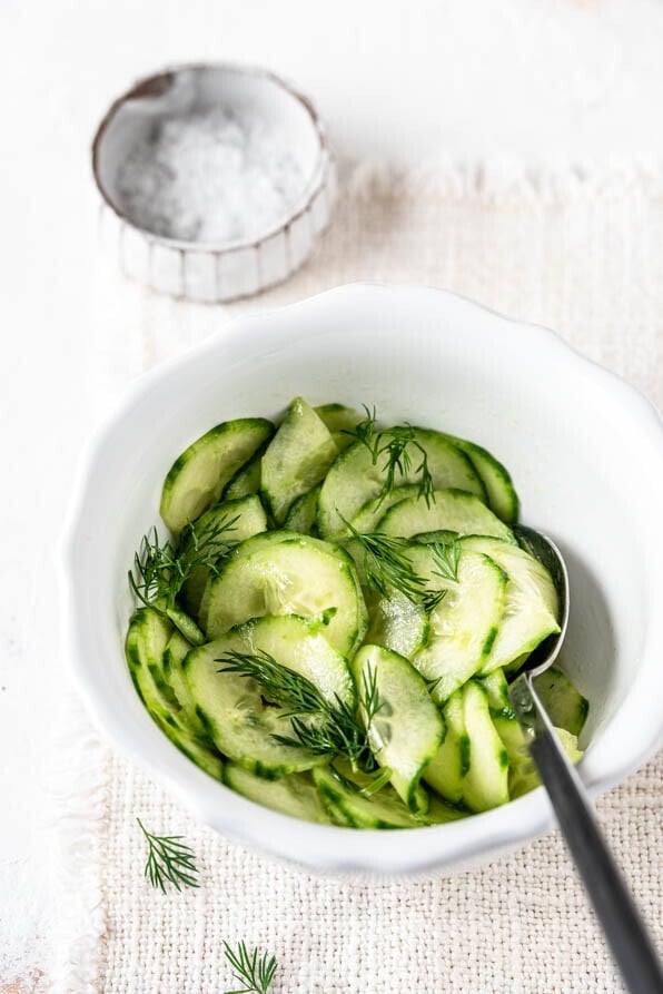 Eine Schüssel Gurkensalat neben Schälchen mit Salzflocken