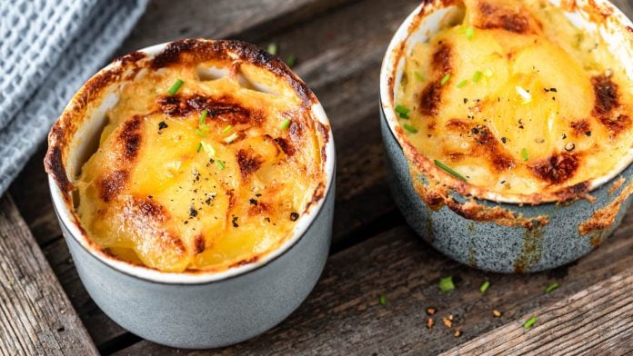 Zwei Förmchen Kartoffelgratin auf Holzuntergrund