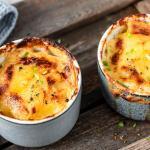 Zwei Förmchen Kartoffelgratin auf Holzuntergrund