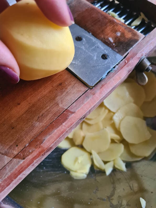 Kartoffeln werden mit einem Gemüsehobel in Scheiben geschnitten.