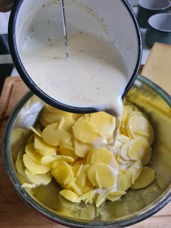Milch wird über die Kartoffelscheiben gegossen.