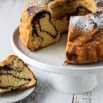 Aufgeschnittener Marmorkuchen auf Etagere und ein Teller davor.