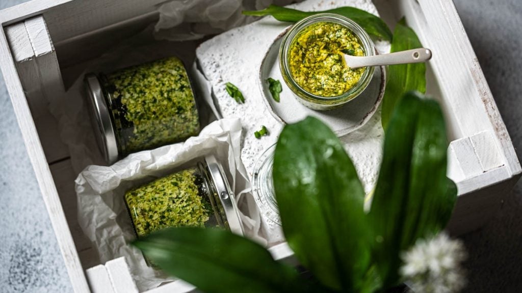 Bärlauch Pesto steht mit einzelnen Zutaten am Tisch
