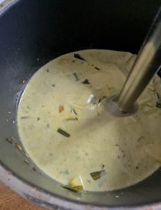 Suppe in Kochtopf wird mit Stabmixer püriert.