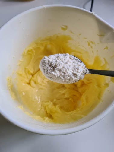 Ein Löffel Mehl wird in Teigmasse gegeben.