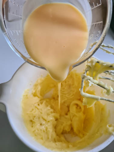 Eierlikör für Eierlikörkuchen wird in Teigmasse gegossen.