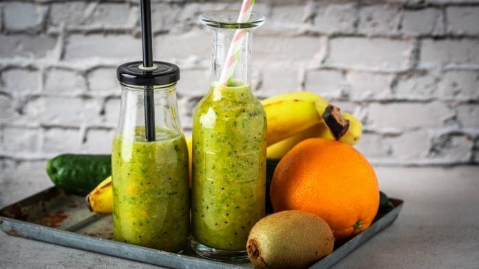 Zwei Flaschen mit grünem Getränk und Obst.