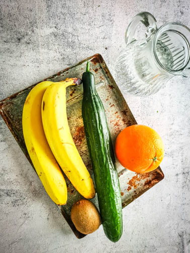 Ein Tablett mit Gurke, Banane, Kiwi und Orange.