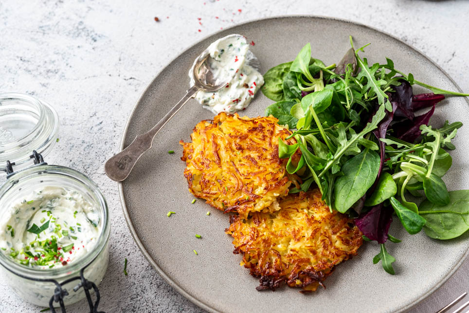 Kartoffelrösti mit Kräuterquark und Salat auf einem Teller