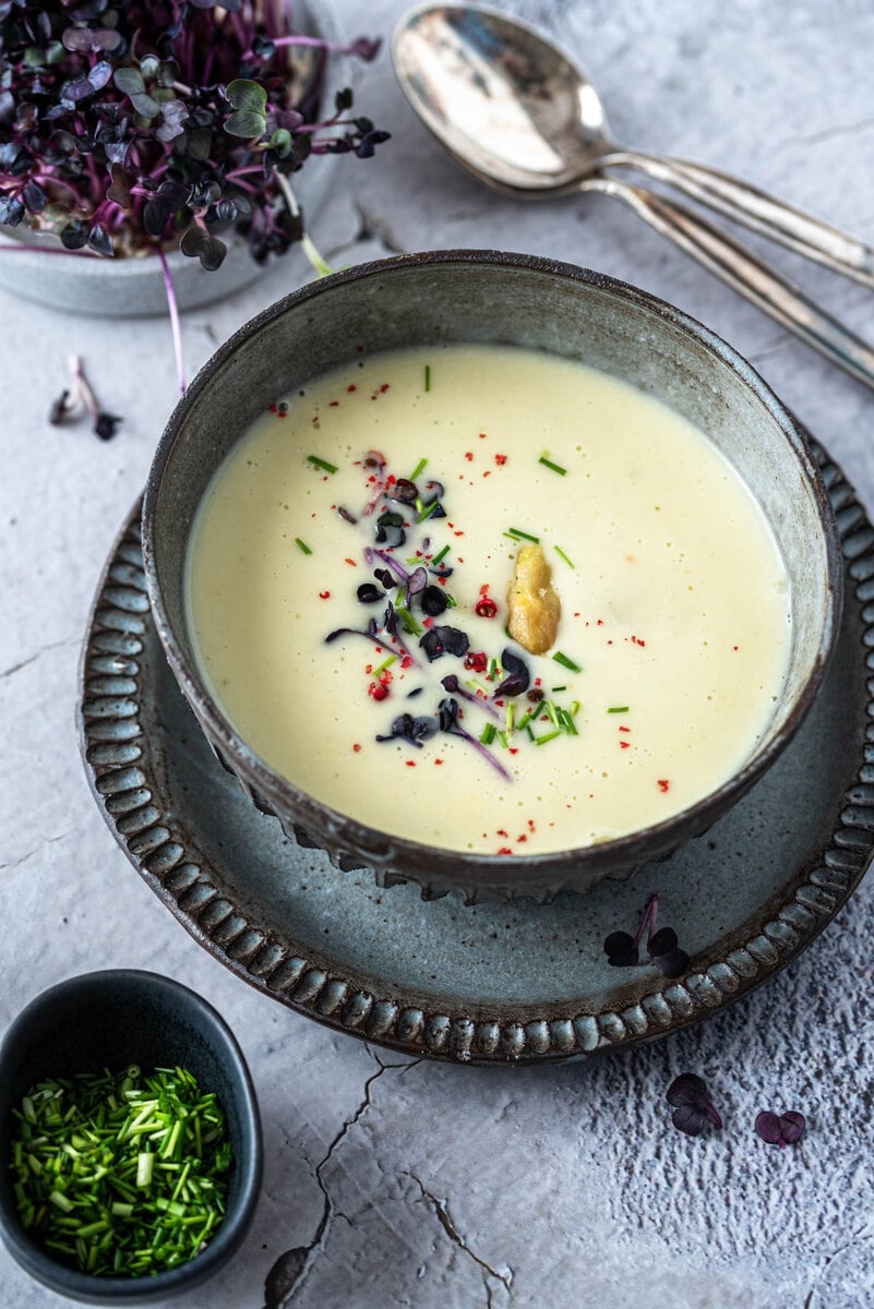 Spargelcremesuppe in Schale mit roter Kresse und Schnittlauch