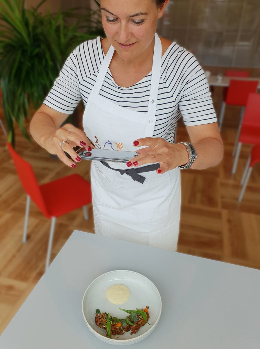 Jemand fotografiert einen Teller mit einem Handy.