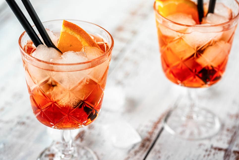 Zwei Gläser Aperol Spritz mit Eiswürfeln und Strohhalm